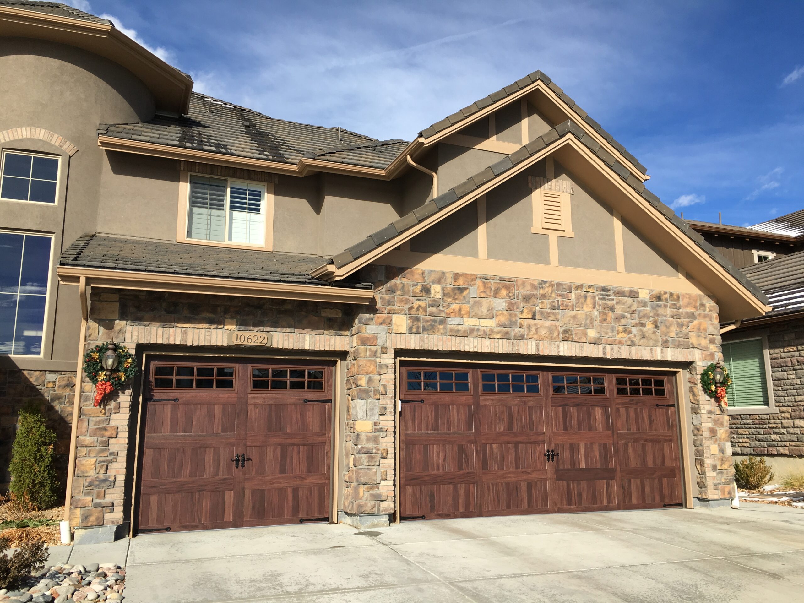 After: Carriage House Garage Door Upgrade with Prairie Grid Windows on Stone Accent Craftsman-Style Home